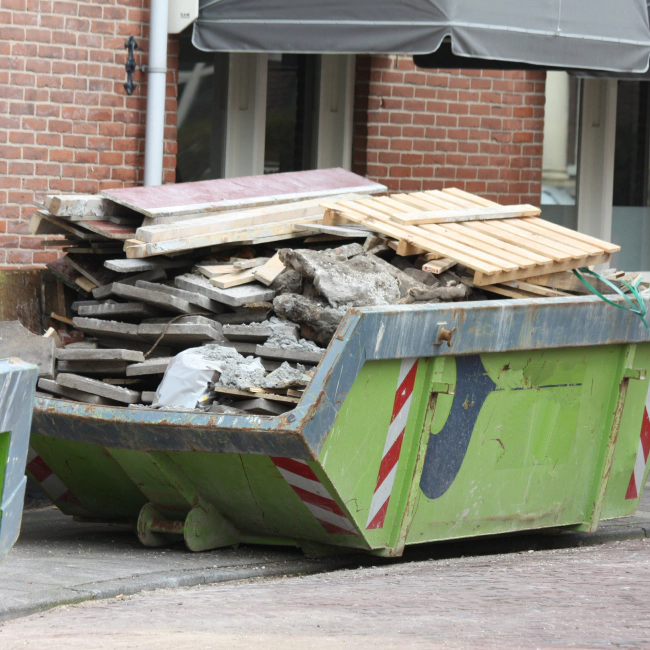 debris piled up inside green dumpster